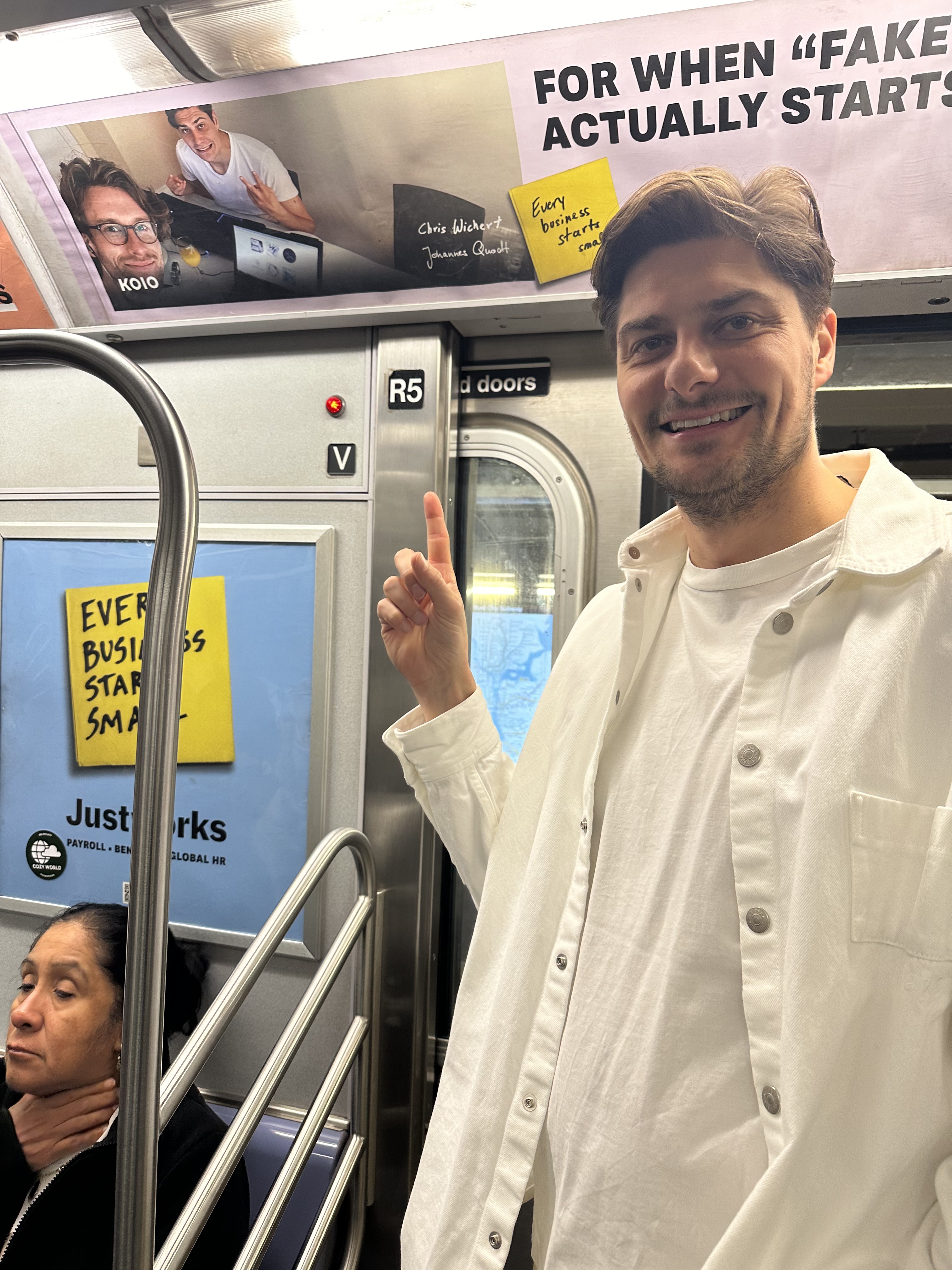 Chris Wichert pointing at a Koio ad on the NYC subway